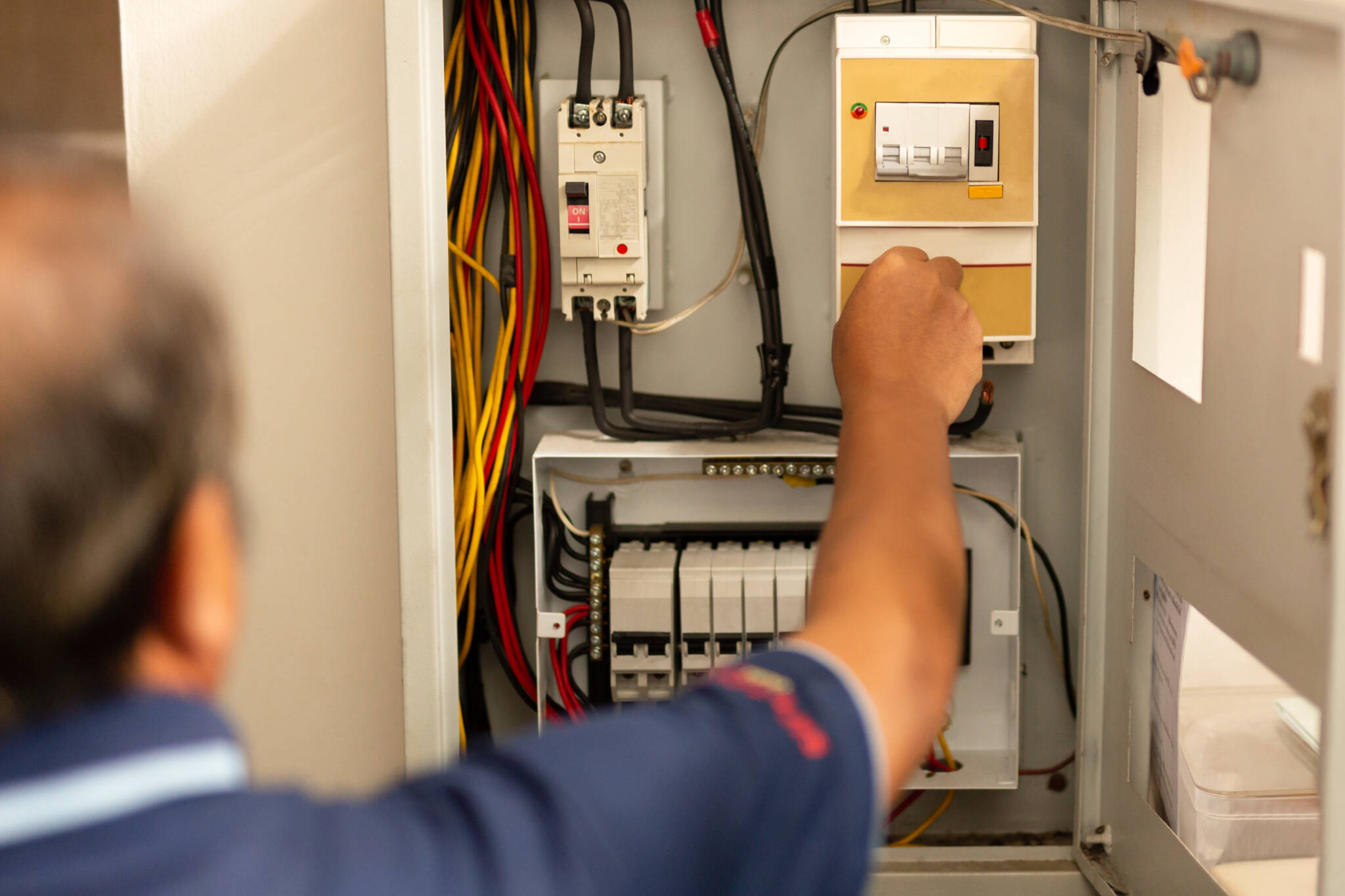 Senior Electrician Measuring Voltage In Fuse Board.
